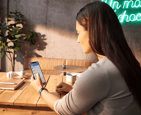 A woman using Outlook for iOS to check her email on her iPhone